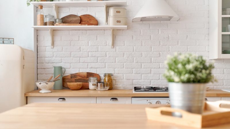 Open shelves, jars, cutting boards, and a potted plant add affordable decorative items to a small kitchen