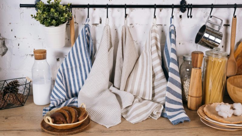 Striped dish towels, jars, and wooden utensils add colorful accents to a small kitchen counter