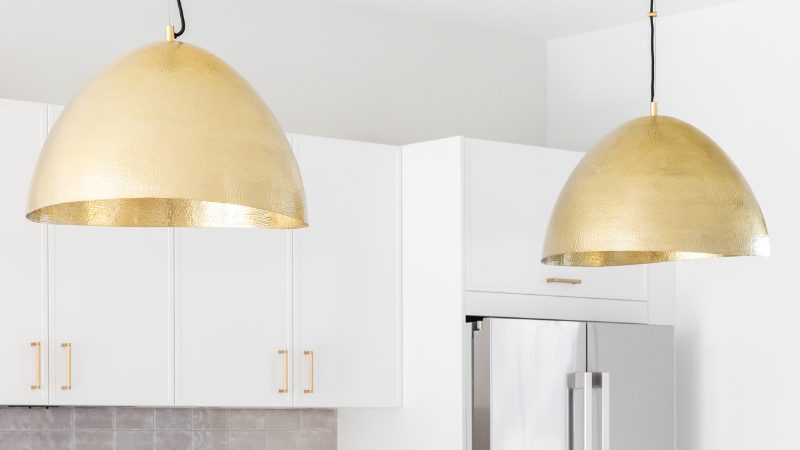 Gold pendant lights hang above white cabinets in a modern small kitchen