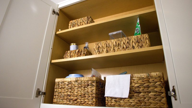Woven baskets neatly organize items inside a small kitchen cabinet